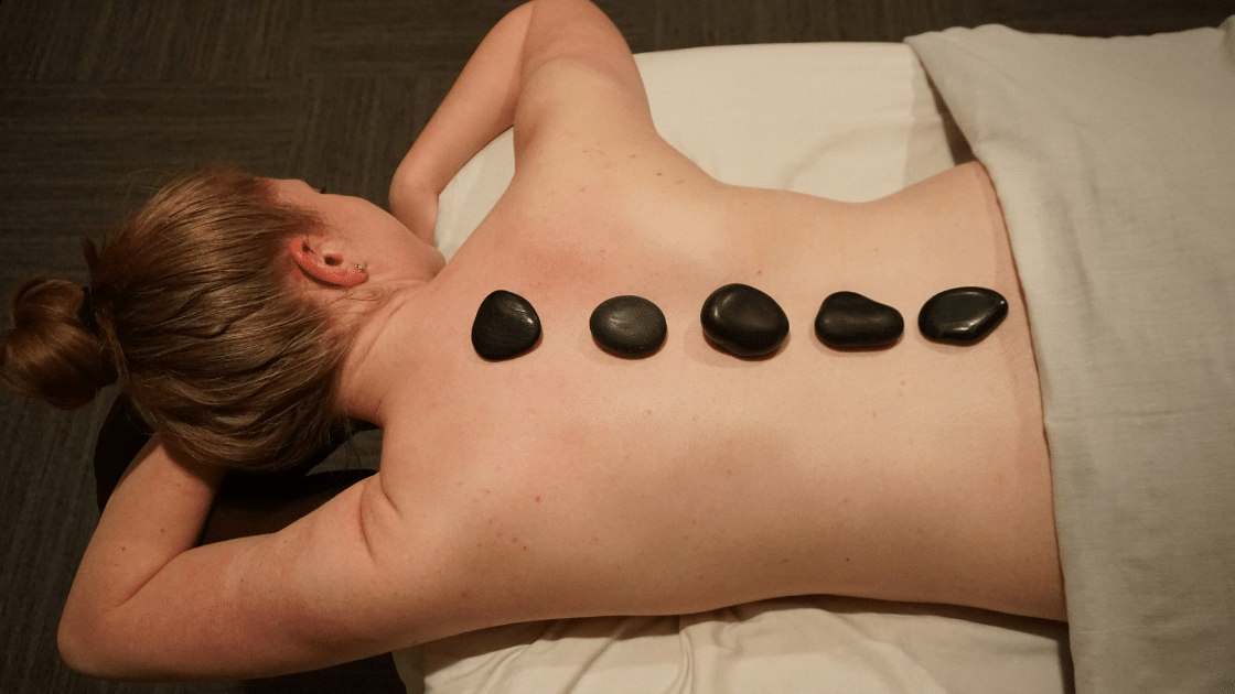 girl receiving hot stone massage with rocks on back