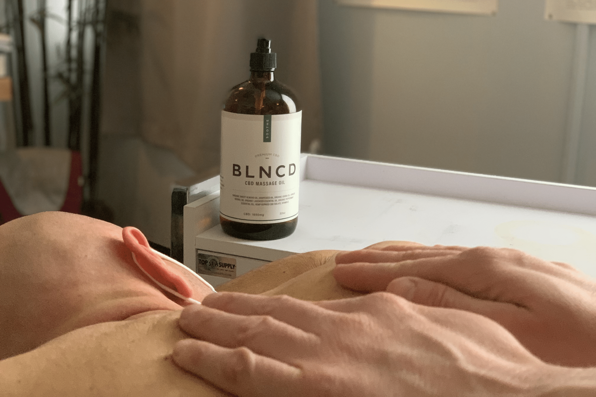 man getting a cbd massage with a cbd massage oil in the background