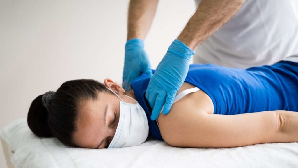 person getting a neck and back massage with a face mask on