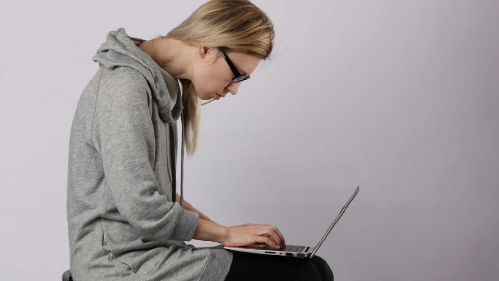 woman hunched over typing on computer