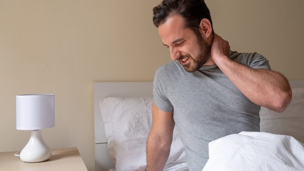 Man waking up with neck pain in bed