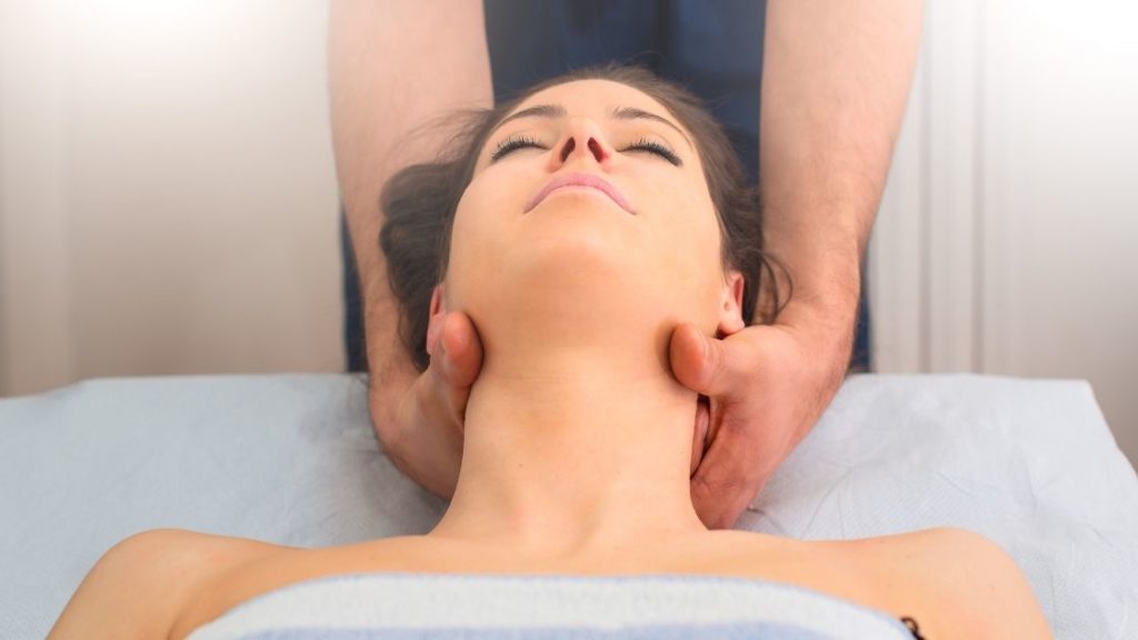 female patient receiving cranial sacral therapy with massage therapists hands on her neck