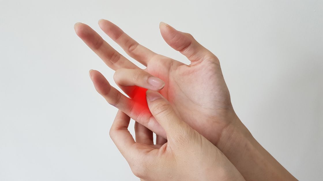person grabbing hand with trigger finger pain in red
