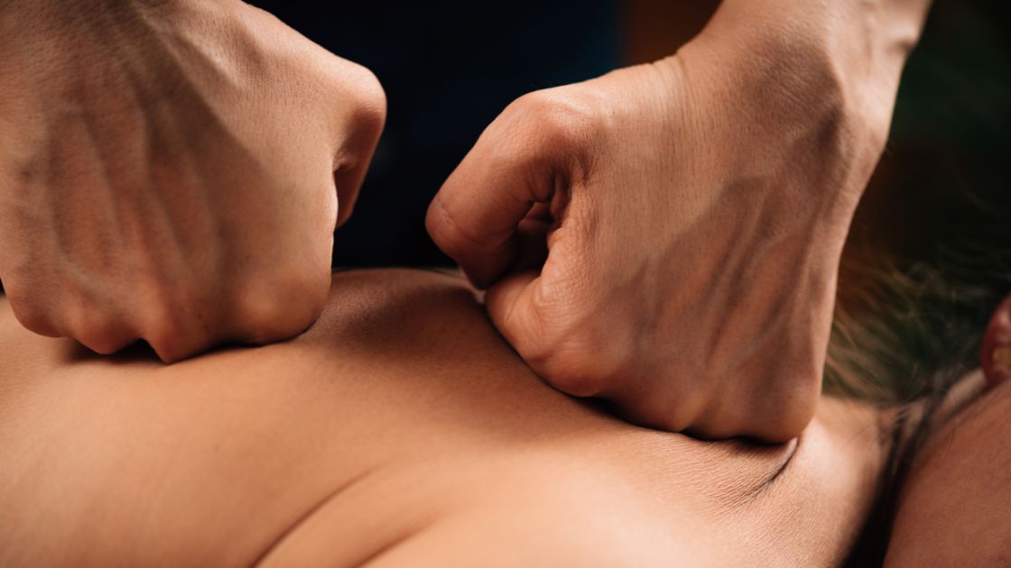 massage therapist using their fists on clients back during a firm pressure massage