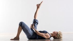 woman in dark clothes laying on back doing a lying hamstring stretch