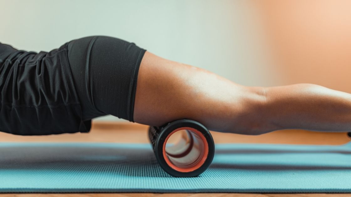person rolling quadriceps on a foam roller, only the legs and mid body are visible