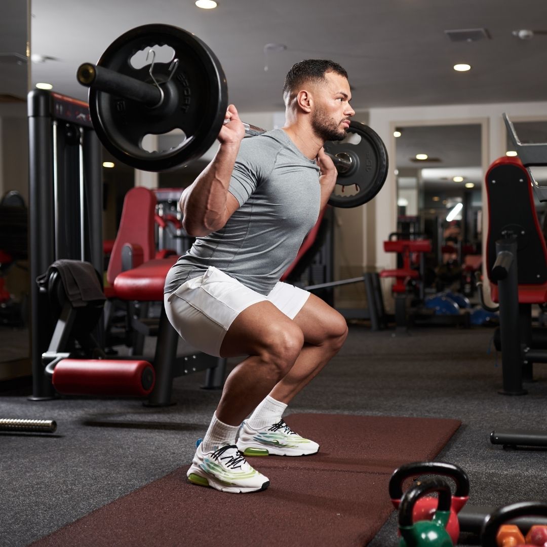 man performing a barbell squat in the gym