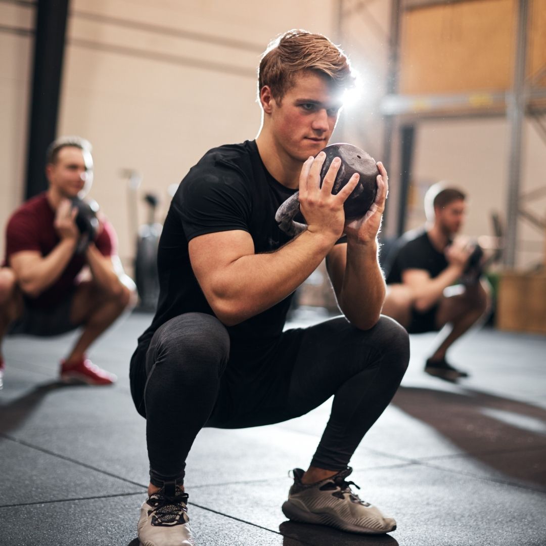 man performing a goblet squat with kettlebell in the gym