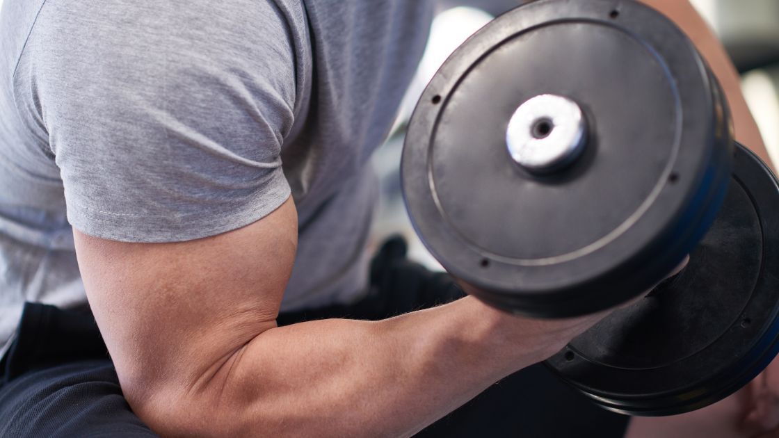 man doing dumbbell curls, closeup of the arm