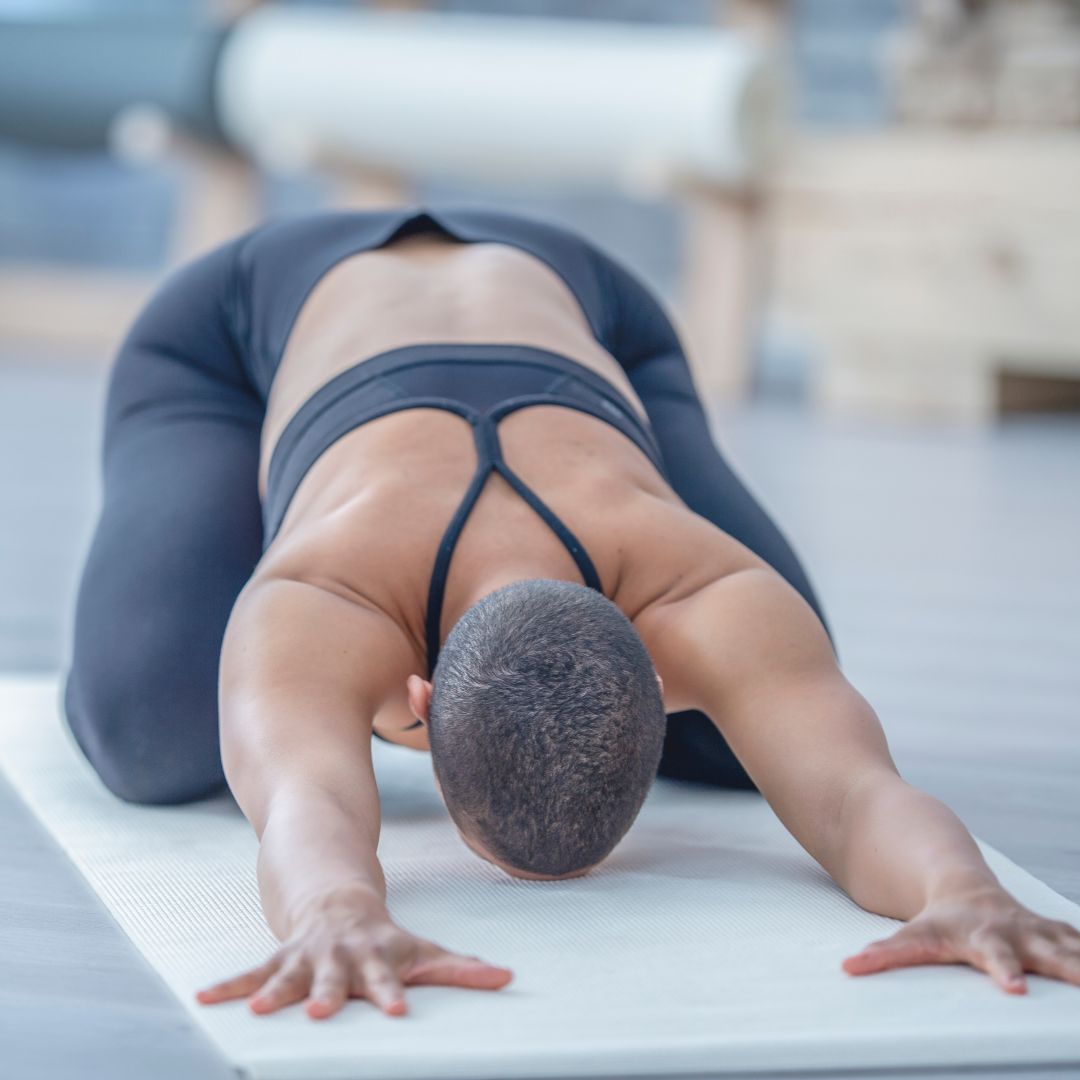 woman doing child's pose on a yoga mat