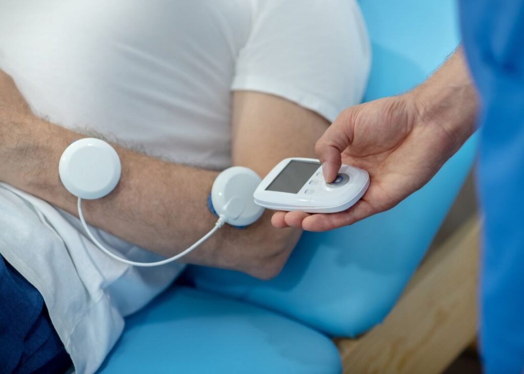 close up of patient lying on treatment bed having forearm muscles stimulated