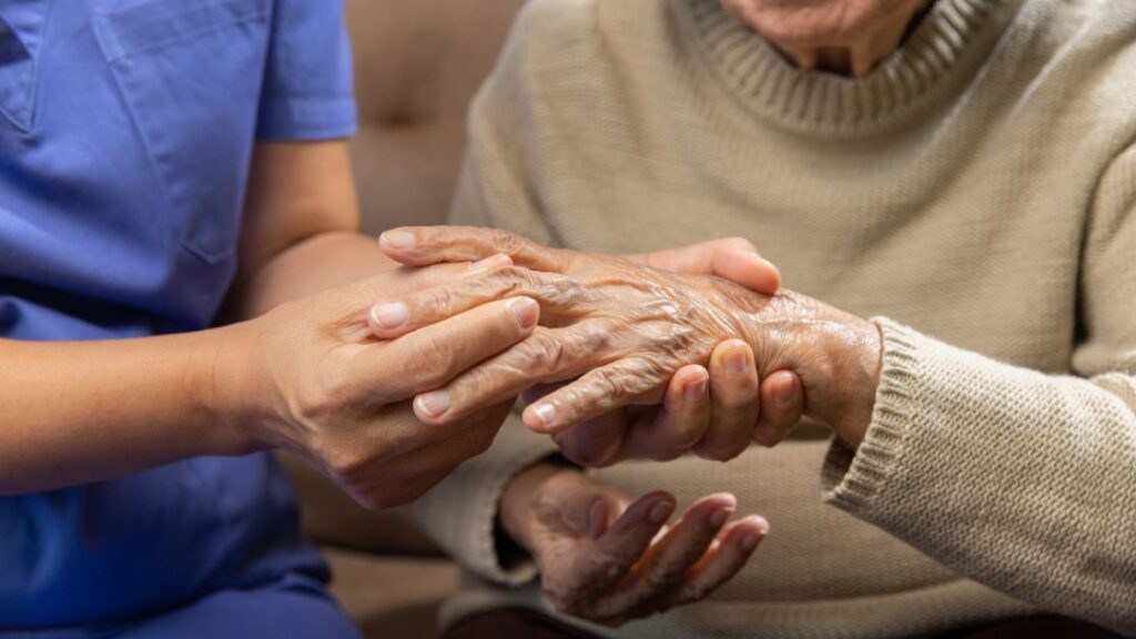 caregiver massaging wrist of elderly woman