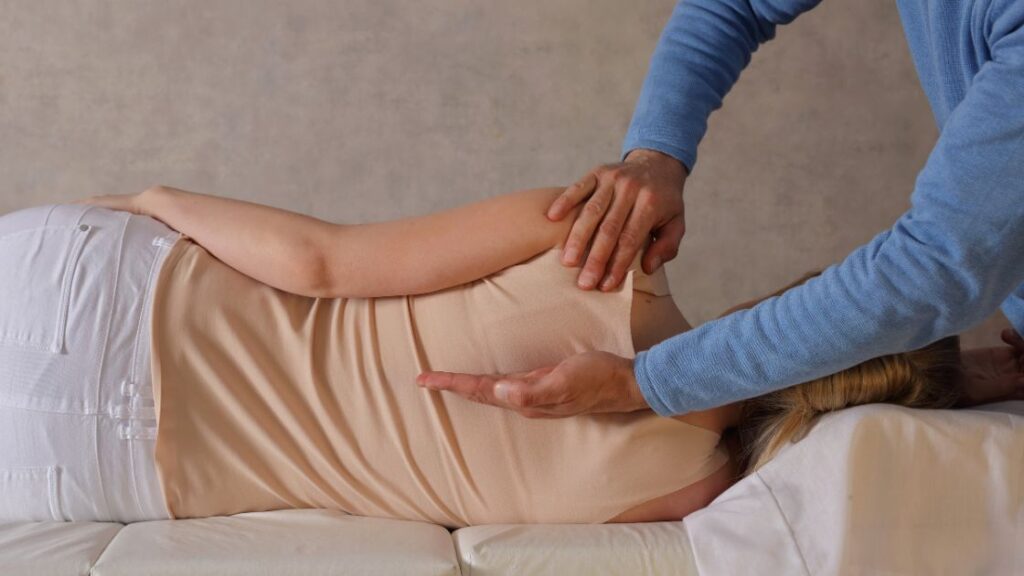 chiropractor adjusting woman's back while laying on her side