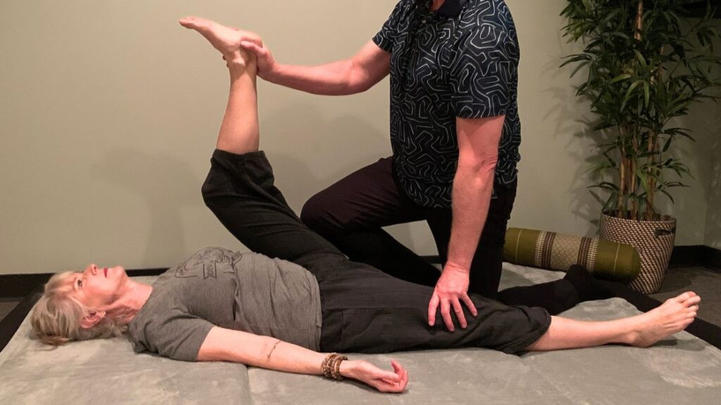 female client being stretched on the floor by massage therapist