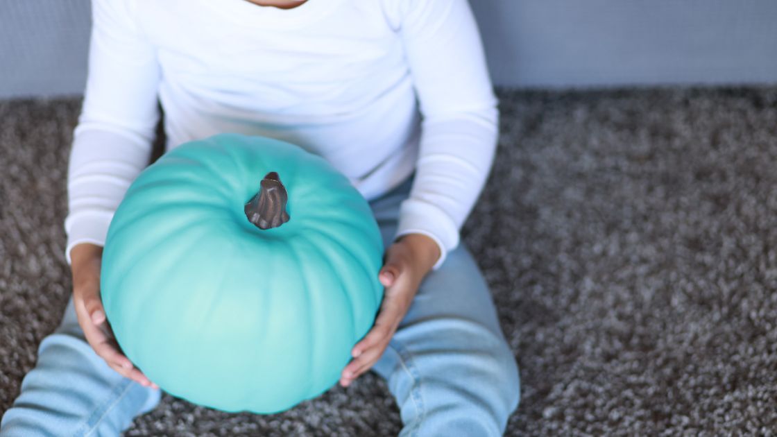 girl holding a teal pumpkin in her lab