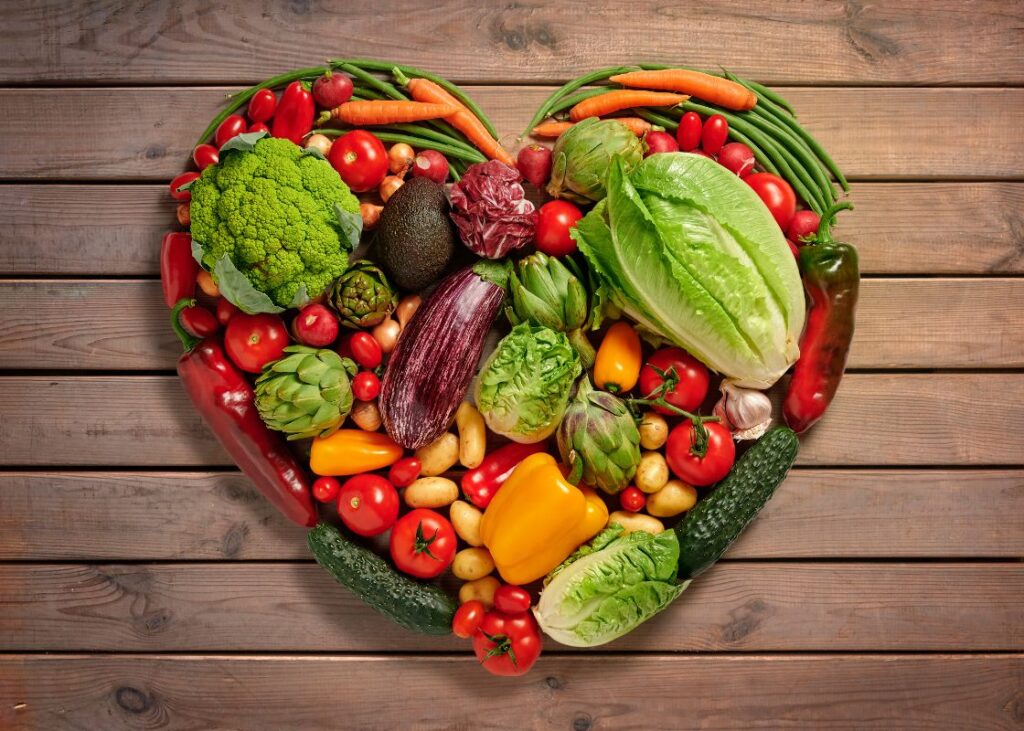 fruits and vegetables laying in the shape of a heart