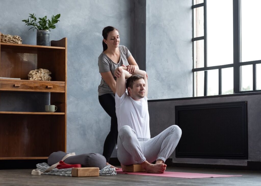 woman performing assisted stretching on male client's shoulders