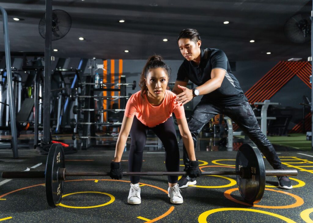 personal trainer assisting client with a deadlift