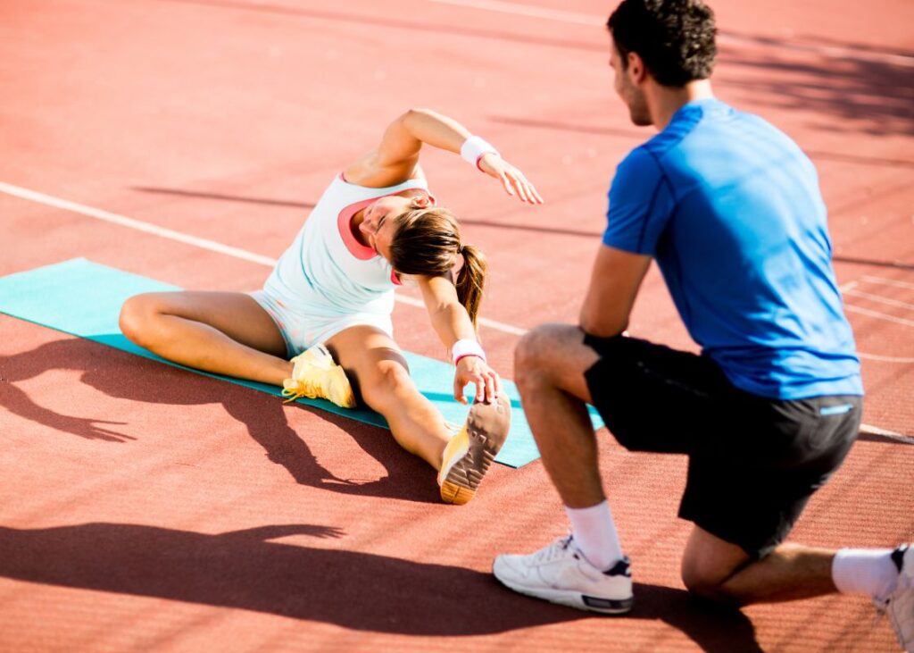 woman stretching outside with personal trainer