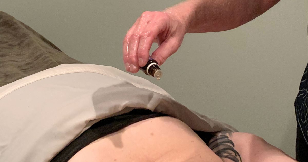 detoxifying raindrop therapy essential oils being put onto clients back during a massage