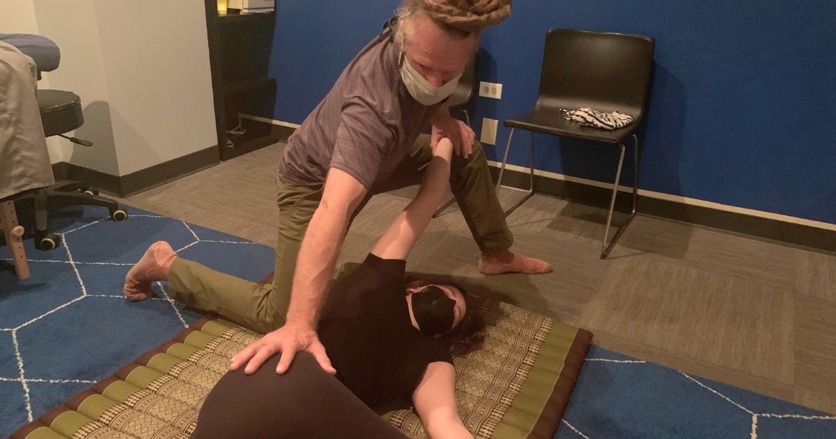 woman being stretched on floor during a Thai Massage