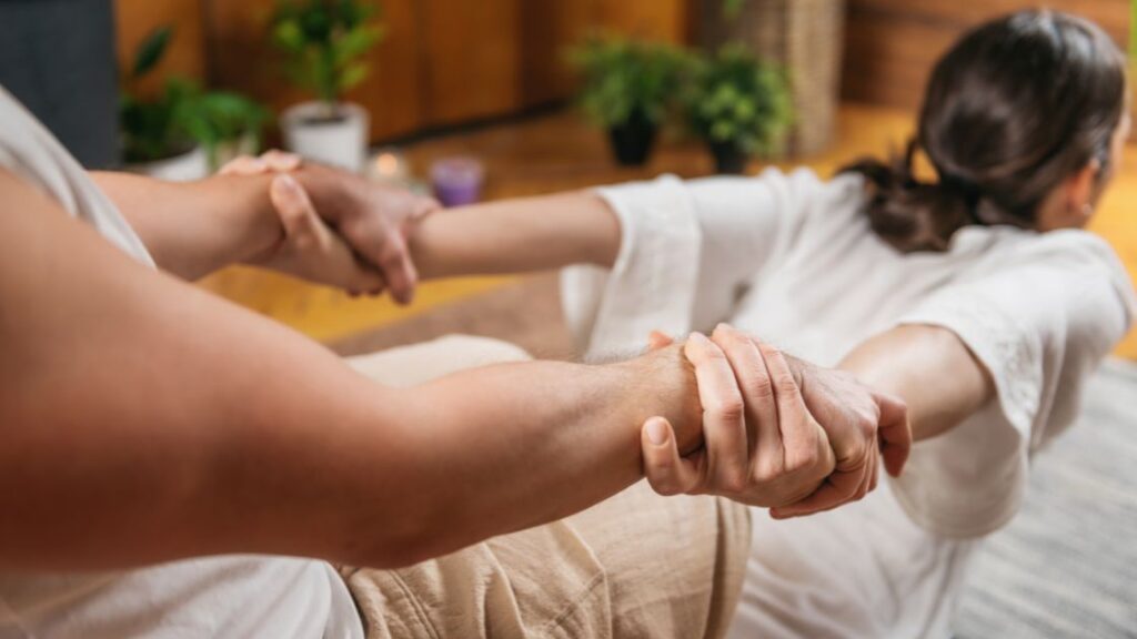 woman receiving a thai yoga massage stretching shoulders and back