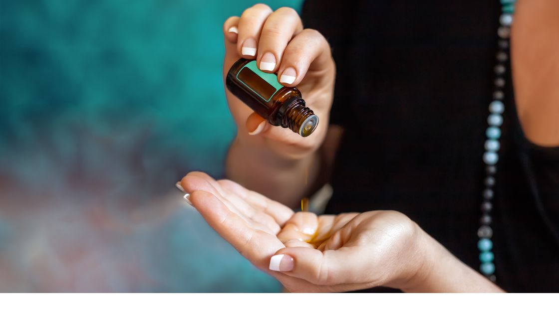 person dripping essential oils into their hand before a raindrop therapy massage