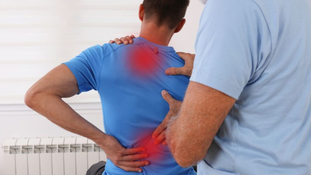 person with pain in between shoulder blades being seen by chiropractor