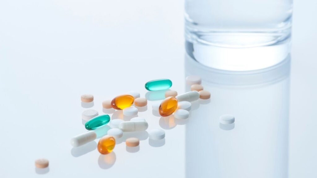 BH – Massage Therapy vs. Pain Medication_ What Are Your Options pills sitting next to a glass of water on a white counter
